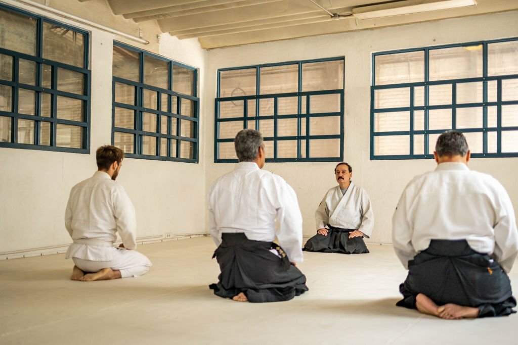 Four men perform concentration exercises before aikido training