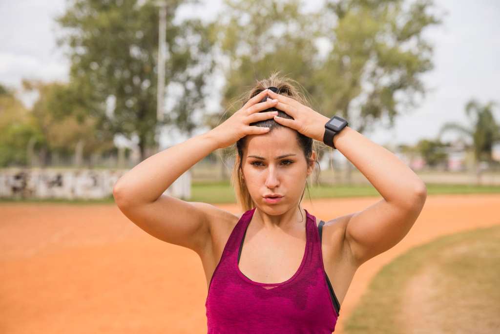 sporty woman stretching on stadium track